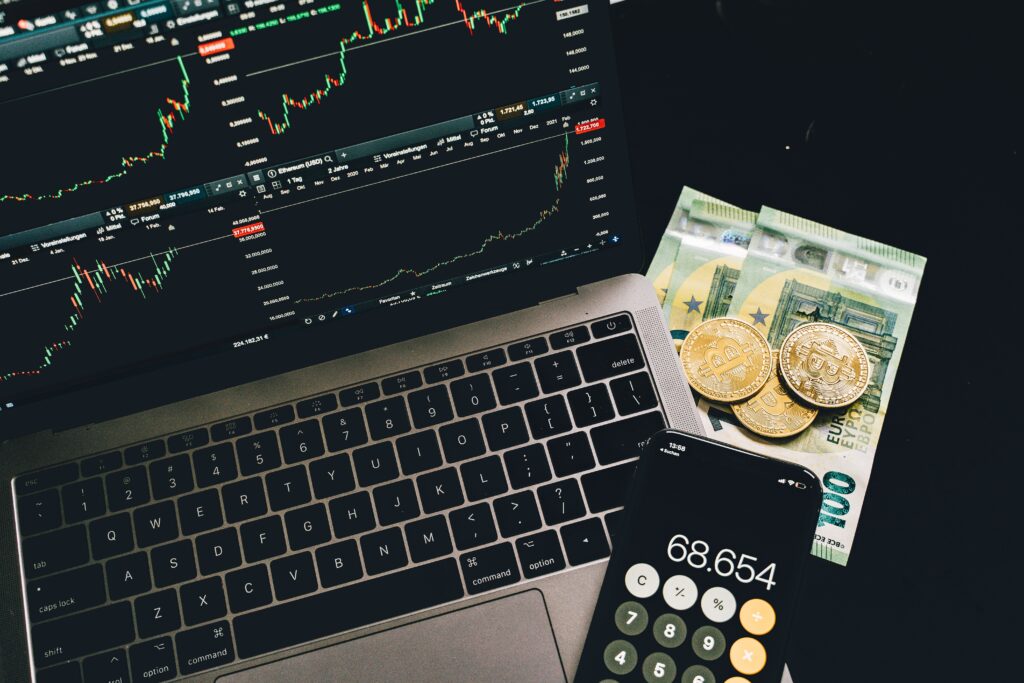 notebook com dadis de criptoativos com dinheiro e um celular com calculadora