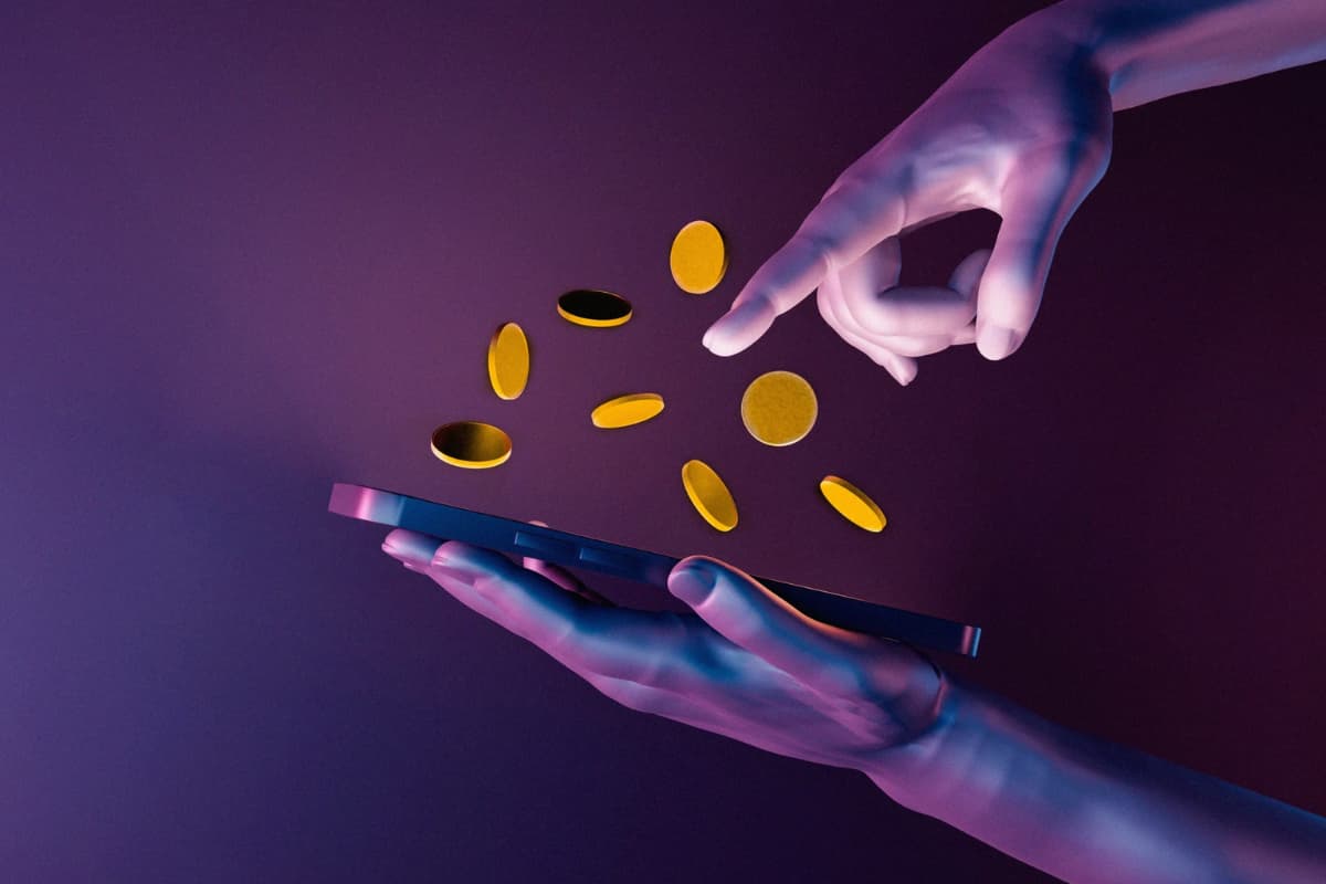 O ChatGPT disse: Mãos interagem com moedas digitais saindo de um tablet, ilustrando criptomoeda: o que é e como funciona na prática.