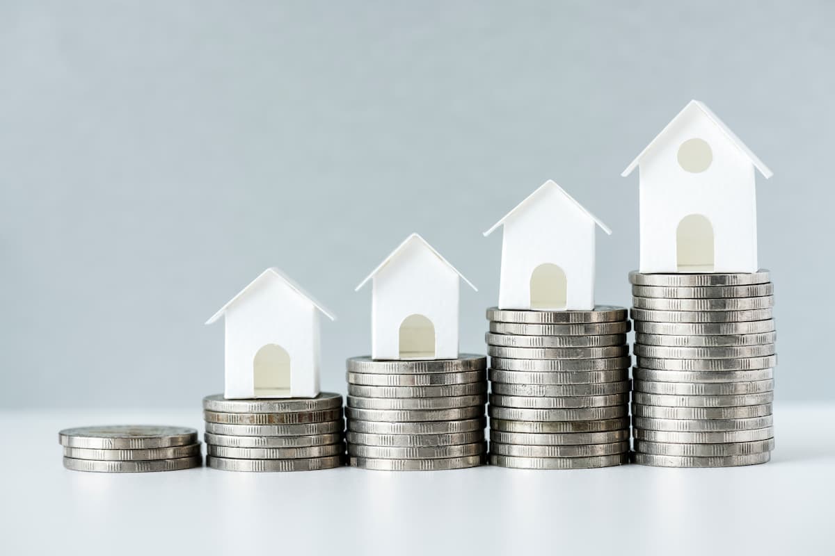 Casas em miniatura sobre pilhas de moedas representam o crescimento dos diferentes tipos de fundos imobiliários.