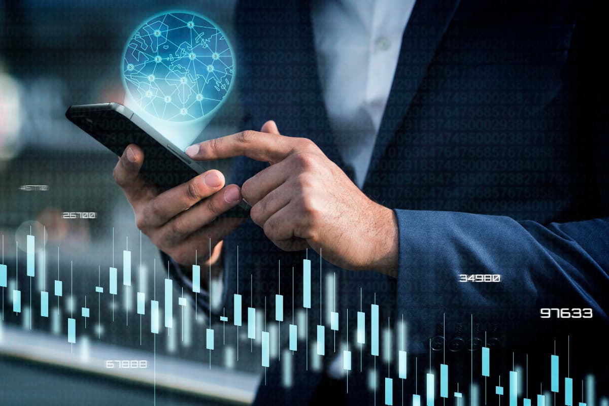 Pessoa usando smartphone com gráficos digitais e holograma global, simbolizando investimentos alternativos em tecnologia financeira.
