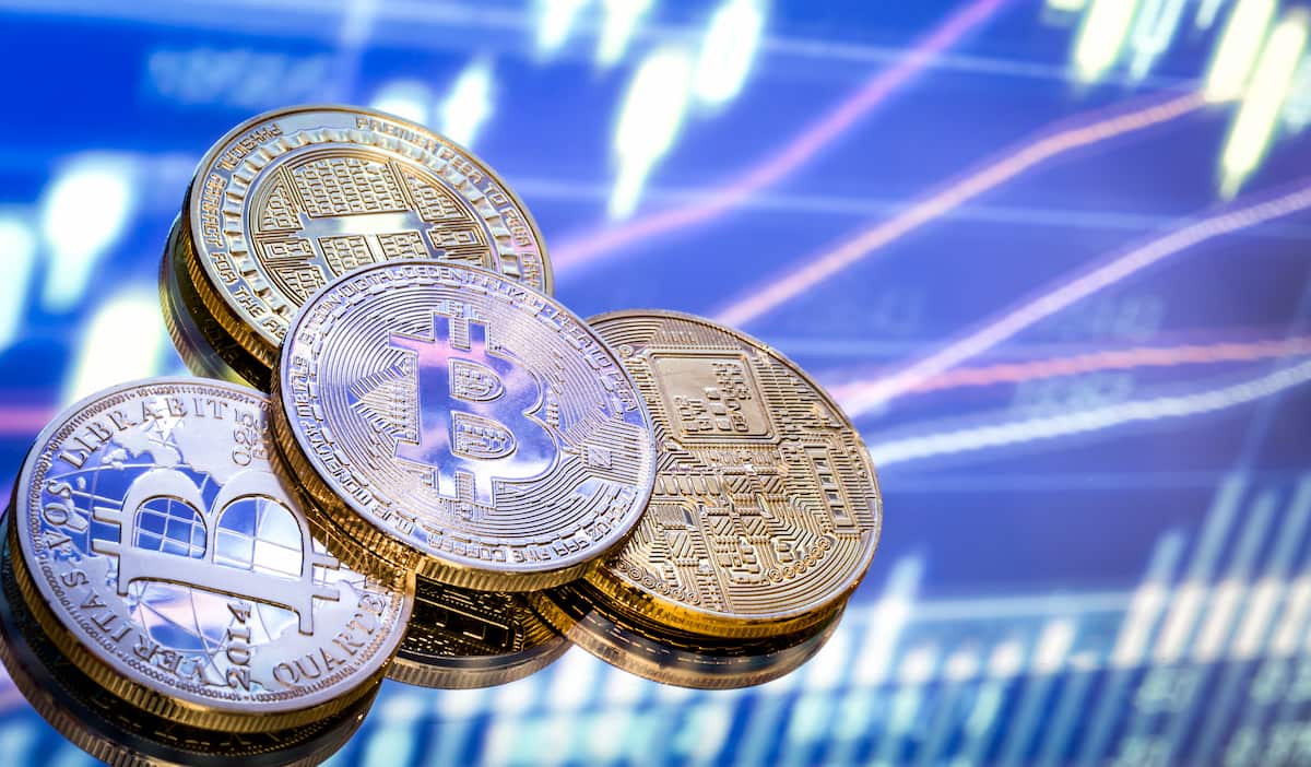 Moedas digitais sobre fundo com gráficos financeiros, levantando a questão: investir em criptomoedas é seguro em 2025?
