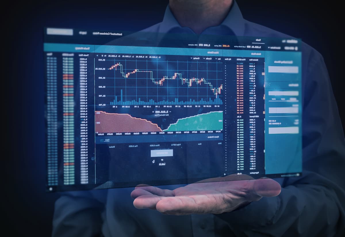 Homem segurando tela com gráficos e dados do mercado financeiro, ilustrando termos do glossário de investimentos.