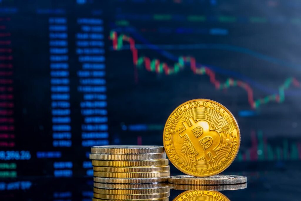 Moedas de bitcoin em destaque com gráfico de mercado ao fundo, ilustrando a dúvida: investir em criptomoedas é seguro?
