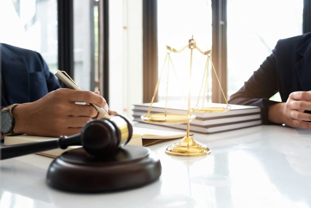 Reunião jurídica com balança da justiça e martelo sobre a mesa, simbolizando tipos de precatórios seguros para investir.