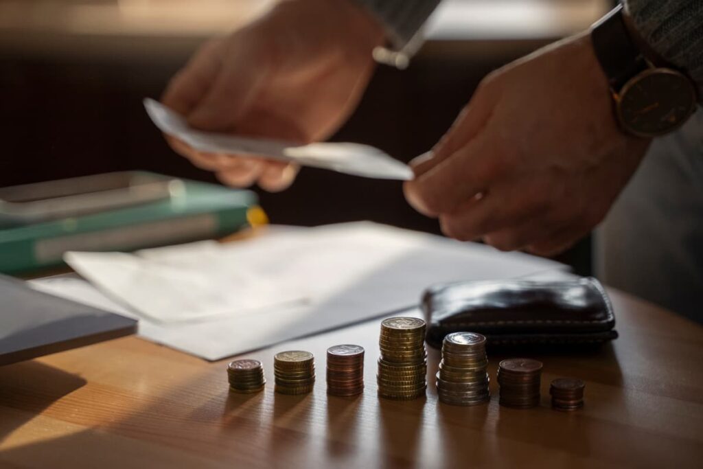 Pessoa organizando documentos e moedas sobre uma mesa, representando a tributação de investimentos no exterior.