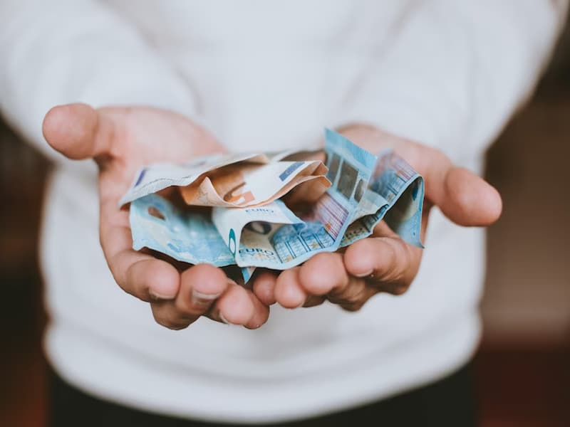 A imagem transmite a ideia de dinheiro sendo oferecido ou manipulado, o que pode ser relacionado à vulnerabilidade do investidor diante de propostas financeiras — especialmente em um mercado sensível como o de ativos judiciais.