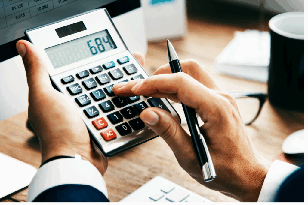 A imagem mostra uma pessoa utilizando uma calculadora, em um ambiente de escritório.