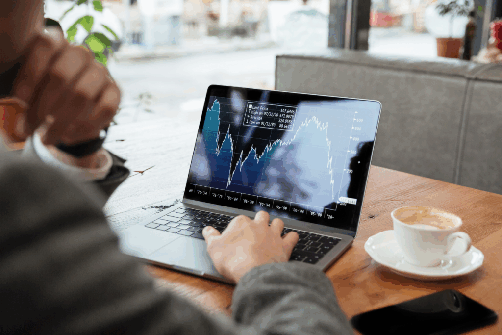 Empresário sentado em um café analisando gráficos e documentos financeiros sobre investimentos