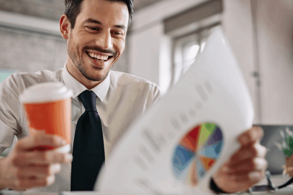 Homem sorridente analisando gráfico colorido de desempenho financeiro enquanto segura um café, representando entusiasmo com bons resultados de investimentos.