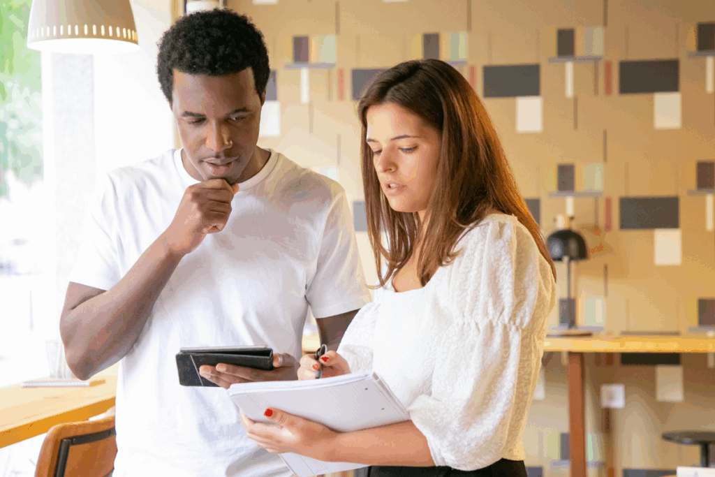 Consultor de investimentos em reunião com cliente, discutindo a estratégia para investir em imóveis sem comprar e fazendo anotações.