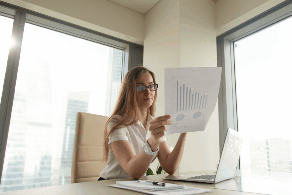 Empresária analisando documentos financeiros com gráficos de crescimento, representando o estudo do ponto de equilíbrio (breakeven) e tomada de decisões estratégicas de investimento.