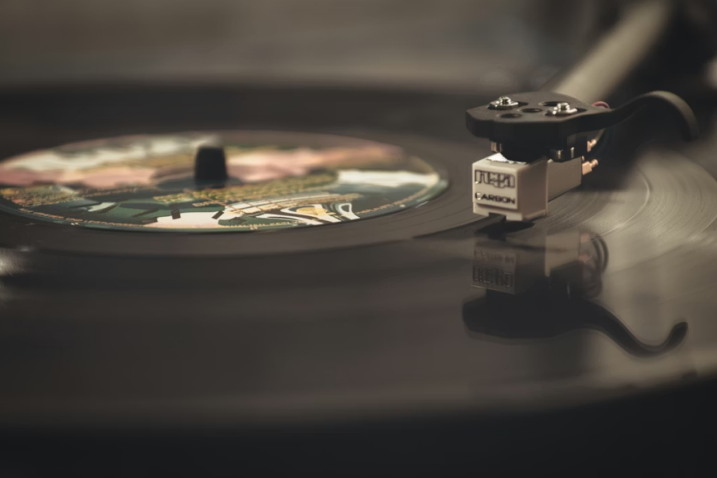 Disco de vinil sendo reproduzido em toca-discos vintage, simbolizando a valorização de catálogos musicais clássicos e o crescimento de 45% do formato físico, essencial para a rentabilidade dos Royalties Musicais.