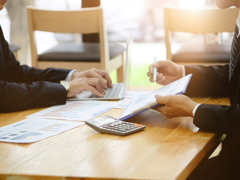 As imagens que mostram close-ups de mesas de reunião destacam o processo de análise de dados, cálculo e tomada de decisão no ambiente de negócios.